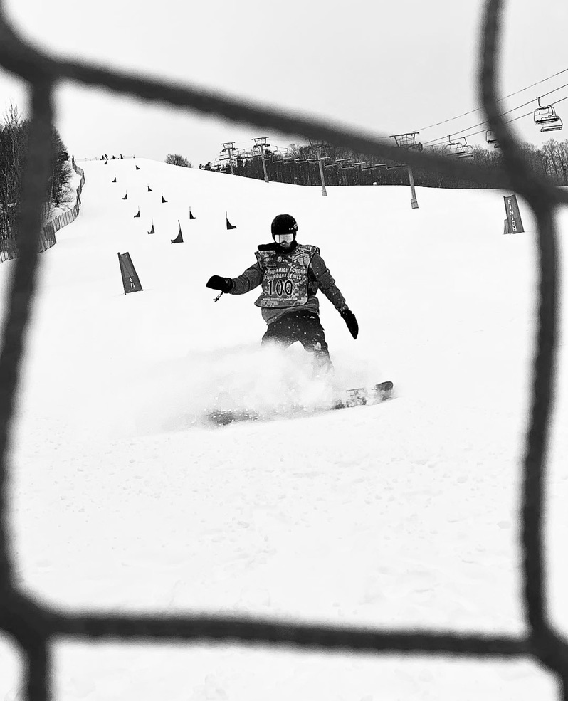 Snowboarder on a slope seen through a fence