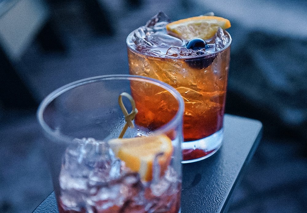 Two old fashioneds with orange and ice