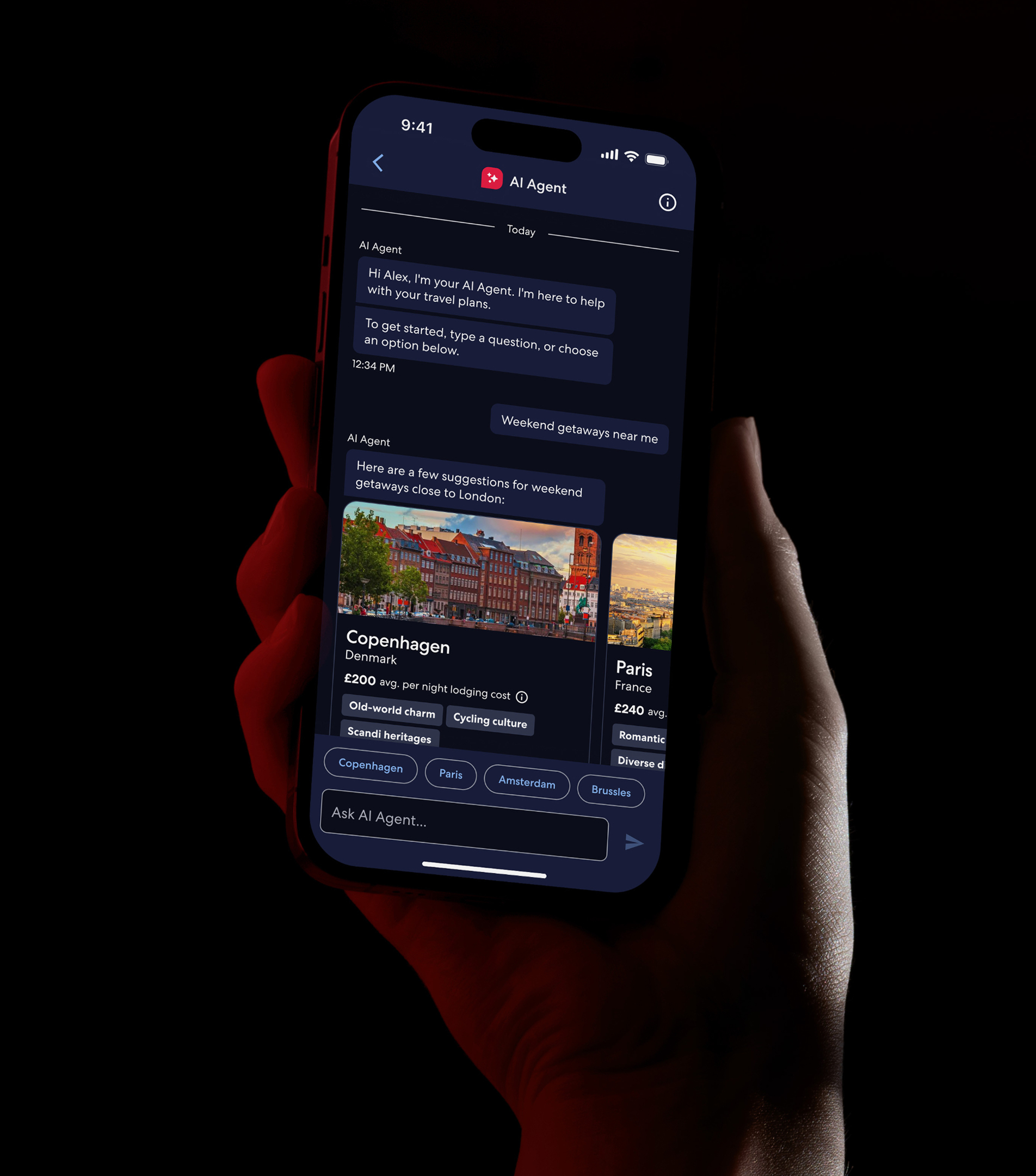 Hand holding a phone showing the Hotels.com AI Agent suggesting weekend getaways